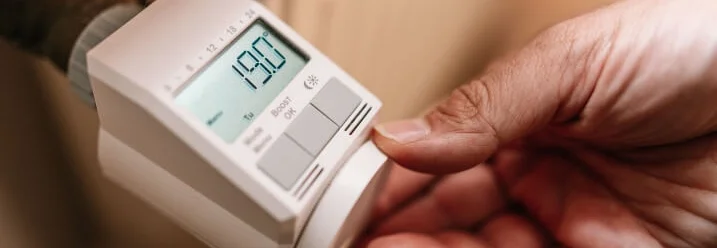 Person stellt Heizkörperthermostat ein